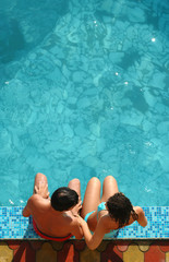 Young pair sits beside water pool