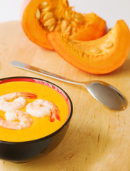 Bowl of warm pumpkin soup decorated with prawns