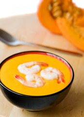 Bowl of warm pumpkin soup decorated with prawns