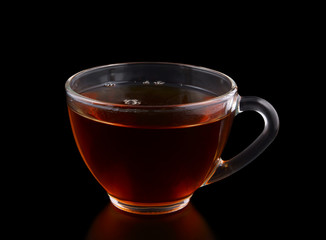 Glass cup of tea on black