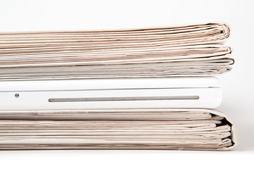 Zeitungsstapel mit Laptop dazwischen