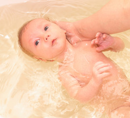 Bathin baby holded by hands.