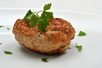 one meat ball with organic parsley on a white plate