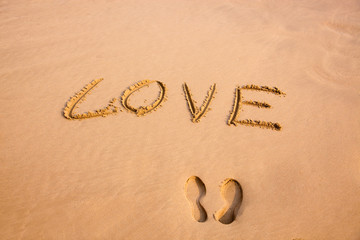 Footprint and handwriting Love in the sand on a beach