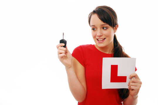 Learner driver holding L plate and car key on white background