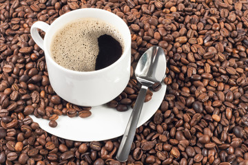 cup of coffee over a lot of coffee beans