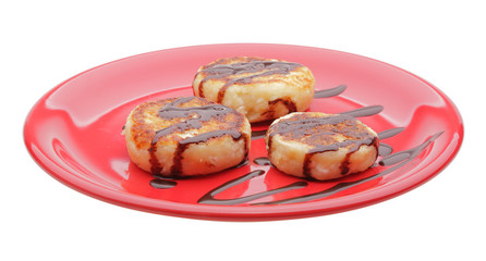 cheese pancakes with chocolate syrup on red plate