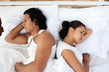Upset couple in bed sleeping separately