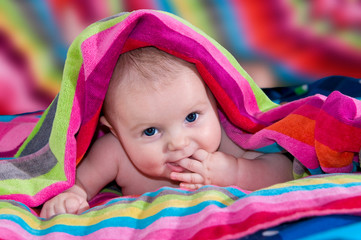Beautiful baby comes out from a colorful blanket