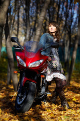 Fototapeta na wymiar The mysterious girl about a red motorcycle among the autumn natu