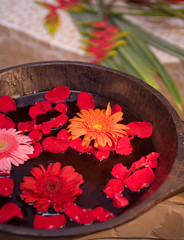 Flower petals floating in a wooden bowl of water