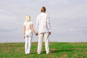 Fototapeta na wymiar Guy and girl standing on the green meadow