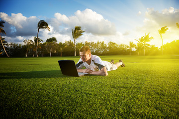 young man whith notebook on the green field