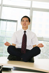 young asian businessman sitting on desk in office