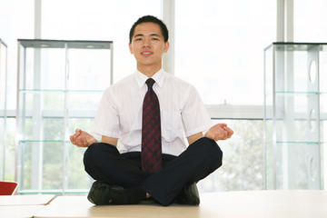 young asian businessman sitting on desk in office