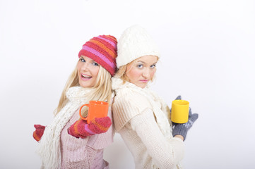 Two young winter woman friends in with cups of tea