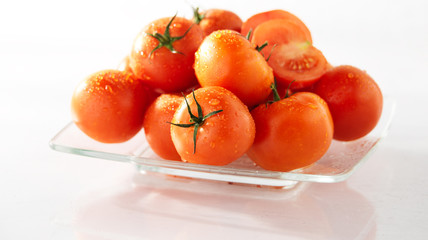 dojrzale czerwone pomidory na talerzu, na białym tle, mokre