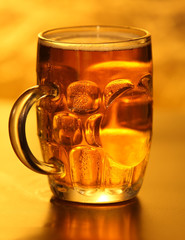 Mug of lager beer with bubbles on yellow