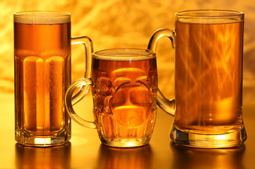 Beer mugs with froth over yellow background