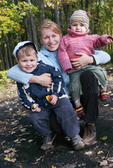 Happy family of mother and two sons in autumn forest