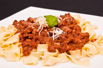 spaghetti bolognese with cheese on white plate
