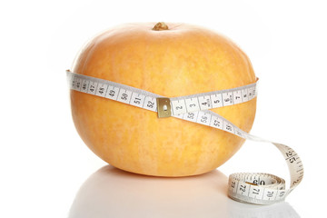 Tape measure wrapped around pumpkin, on white background