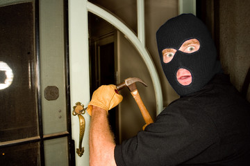 A burglar robbing a house wearing a balaclava.