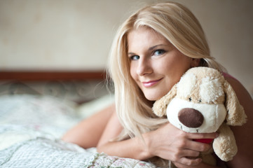 Young beautiful woman relaxing on her bed with a toy
