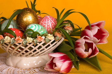 Easter colored eggs and pink tulips in in  basket