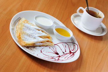 Tea and pancakes  with powdered sugar