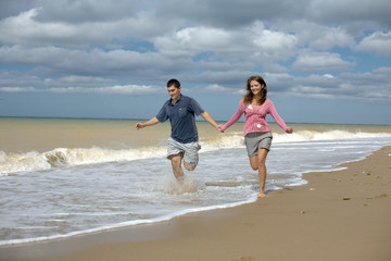 Fototapeta na wymiar Attractive couple running along the seashore