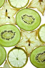 Scheiben von Kiwi, Sternfrucht und Zitrone auf Weiss