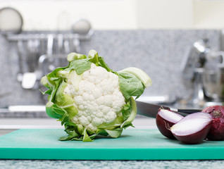 blumenkohl und zweiebeln in der küche auf schneidebrett