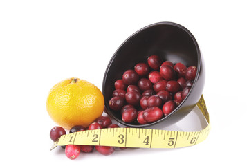 Cranberries spilling out of a Black Bowl with Tape Measure