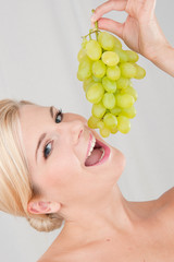 Young healthy smiling woman with white grapes