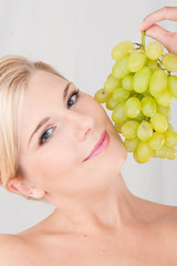 Young healthy smiling woman with white grapes