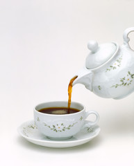 white porcelain teapot pouring black tea isolated on white background