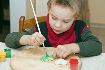 Junge beim Bemalen von Weihnachtsschmuck