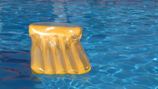 Yellow air bed floating on a swimming pool