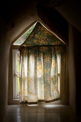 old cottage window with light creeping in behind the curtain