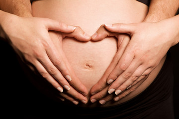 Proud parents making heart shape with hands on belly