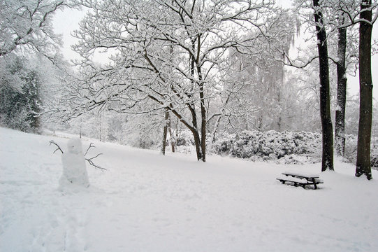 Bonhomme de neige et banc dans un jardin enneigé