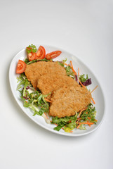 breaded fish steak on a plate with vegetable