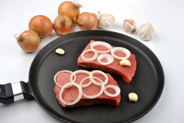 raw organic steak with onion in a pan