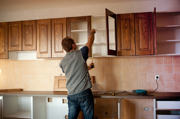 Carpenter working on new kitchen cabinets - obrazy, fototapety, plakaty