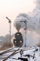 Fototapeta premium Retro pociąg parowy przechodzący przez wieś w okresie zimowym