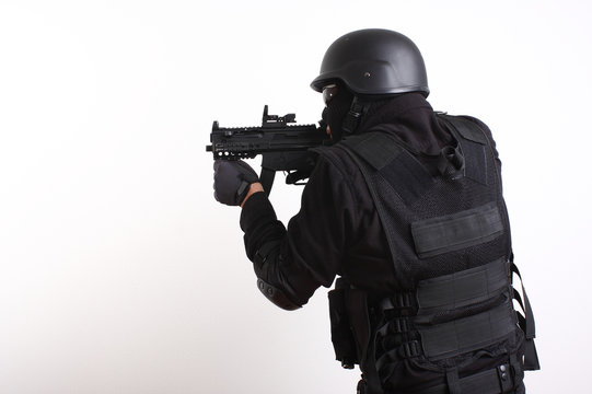 SWAT police officer aiming assault gun.