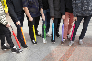 seven teens with closed umbrellas in pedestrian overpass