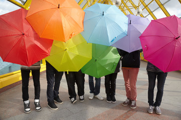 seven teens with opened umbrellas in pedestrian overpass