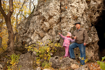 The grandfather and grand daughter are near the cavern